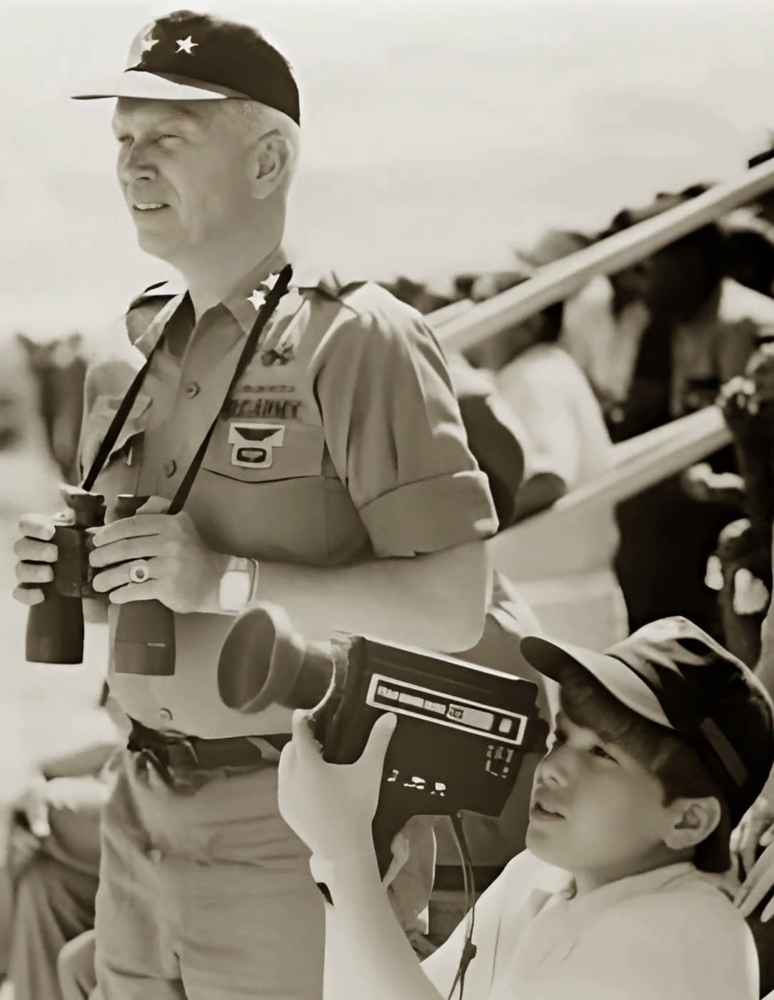 Major General George S. Patton IV with binoculars, beside a boy holding a film camera